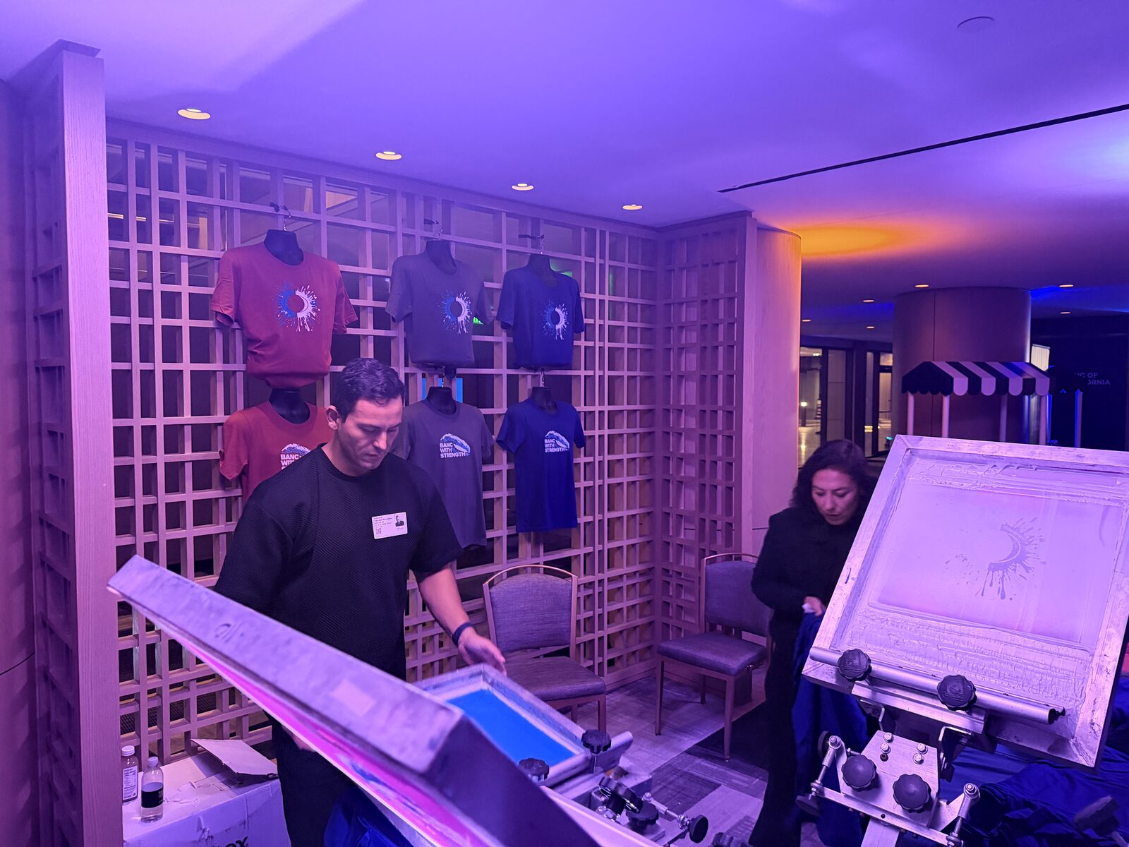 Wall of printed event shirts behind the bar
