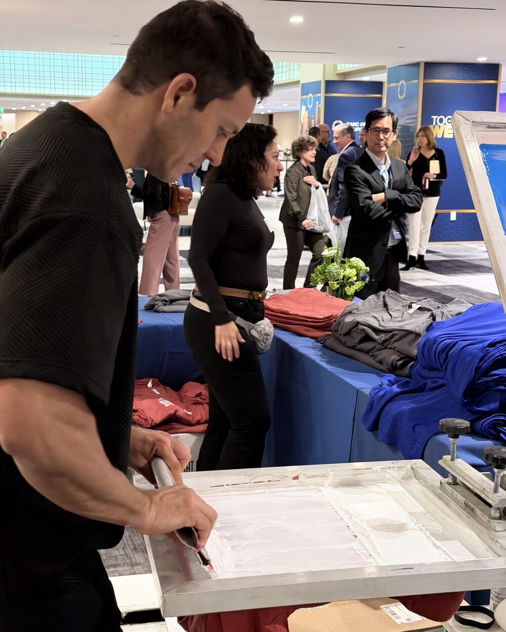Operator pulling a freshly pressed shirt off the heat press at a shirt bar