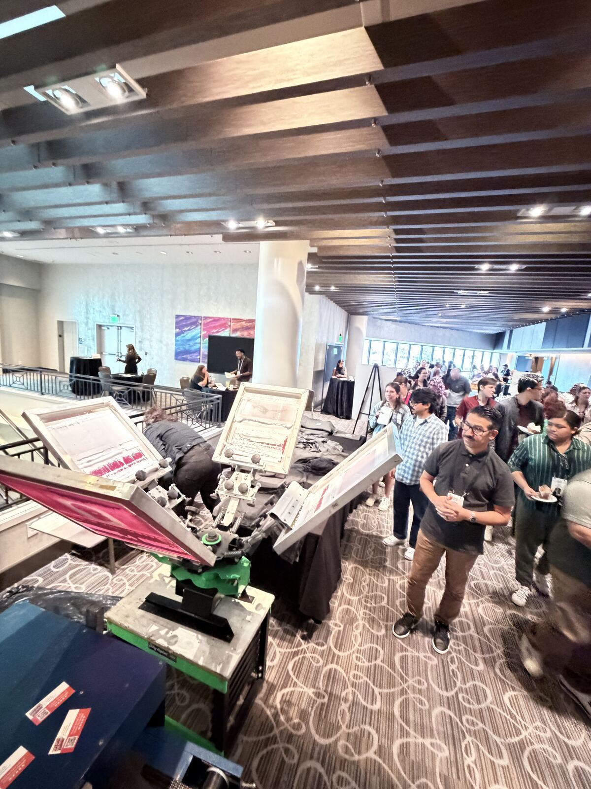 Event attendees engaging with a product booth displaying printed tshirts and apparel in an indoor venue